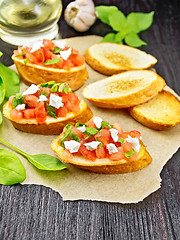 Image showing Bruschetta with tomato and cheese on dark wooden board