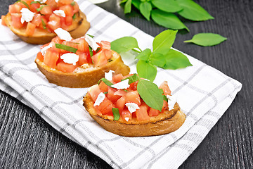 Image showing Bruschetta with tomato and feta on dark wooden board