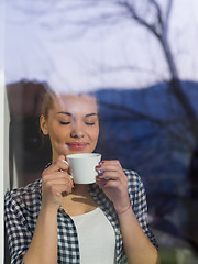 Image showing young woman drinking morning coffee by the window