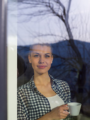 Image showing young woman drinking morning coffee by the window