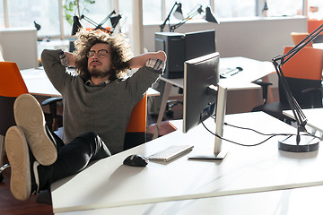 Image showing businessman sitting with legs on desk