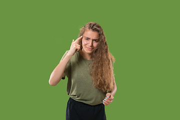 Image showing Beautiful female half-length portrait isolated on green studio backgroud. The young emotional surprised woman