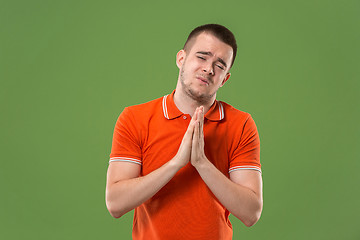 Image showing Beautiful male half-length portrait isolated on green studio backgroud. The young emotional surprised man