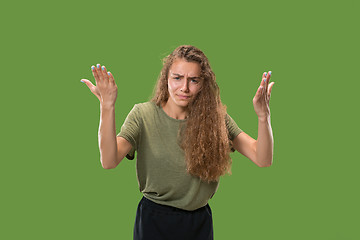 Image showing Beautiful female half-length portrait isolated on green studio backgroud. The young emotional surprised woman