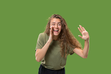 Image showing Isolated on green young casual woman shouting at studio