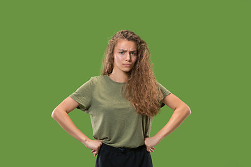 Image showing The serious business woman standing and looking at camera against green background.