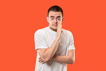 Image showing The young man whispering a secret behind her hand over orange background
