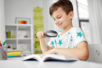 Image showing boy with magnifier reading book at home