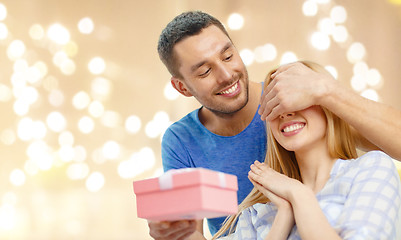 Image showing smiling man surprises his girlfriend with present