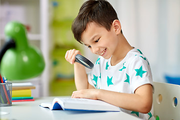 Image showing boy with magnifier reading book at home