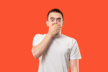 Image showing The young man whispering a secret behind her hand over orange background