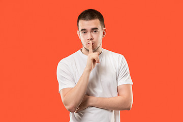 Image showing The young man whispering a secret behind her hand over orange background