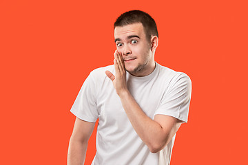 Image showing The young man whispering a secret behind her hand over orange background