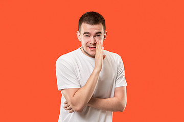 Image showing The young man whispering a secret behind her hand over orange background