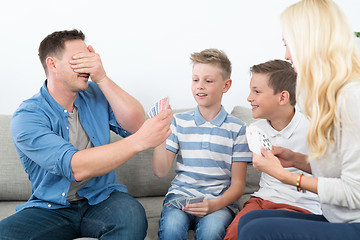 Image showing Happy young family playing card game at home.