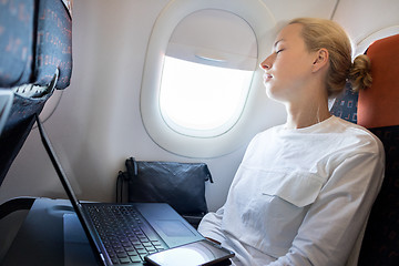 Image showing Tired business woman napping on airplane during her business trip woking tasks.