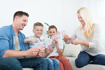 Image showing Happy young family playing card game at home.