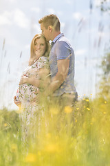 Image showing Young happy pregnant couple hugging in nature.