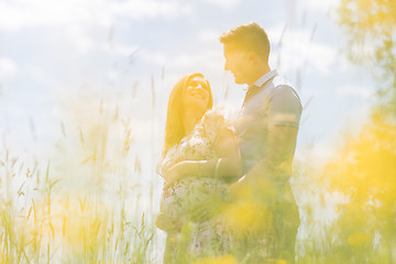 Image showing Young happy pregnant couple hugging in nature.