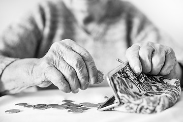 Image showing Detailed closeup photo of unrecognizable elderly womans hands counting remaining coins from pension in her wallet after paying bills.