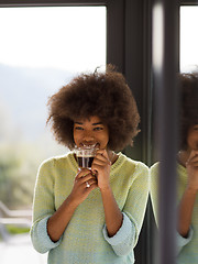 Image showing African American woman drinking coffee looking out the window