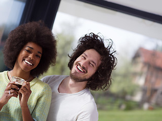 Image showing happy multiethnic couple relaxing at modern home indoors