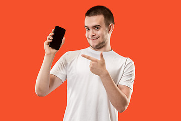 Image showing The happy man showing at empty screen of mobile phone against orange background.