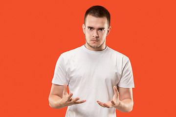 Image showing The young emotional angry man on orange studio background