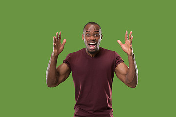 Image showing The young emotional angry man screaming on green studio background