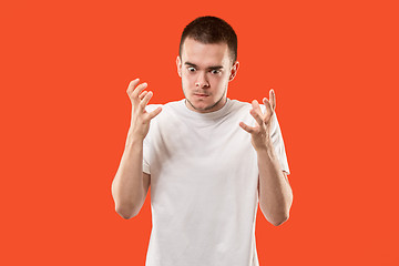 Image showing The young emotional angry man on orange studio background