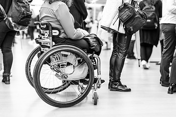 Image showing Close up of unrecognizable hanicapped woman on a wheelchair queuing in line to perform everyday tasks.