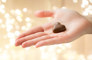 Image showing close up of hand with heart shaped chocolate candy