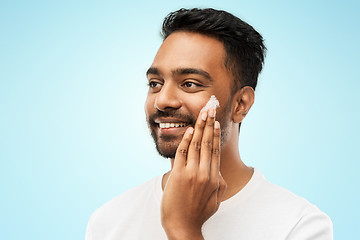 Image showing happy indian man applying cream to face