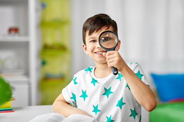 Image showing happy boy looking through magnifier at home