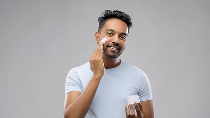 Image showing happy indian man applying cream to face