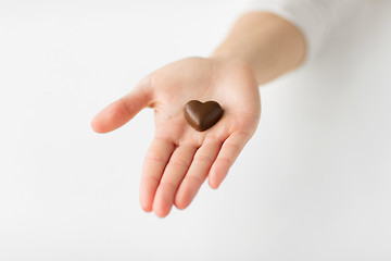 Image showing close up of hand with heart shaped chocolate candy