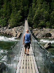 Image showing Man walking on a suspension bridge