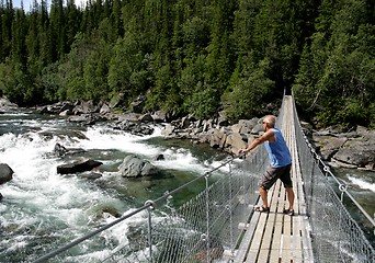 Image showing Man standing on a suspension bridge