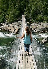 Image showing Woman walking on a suspension bridge