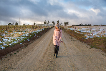 Image showing Woman walking down a country road in winter