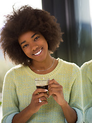 Image showing African American woman drinking coffee looking out the window