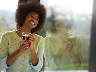 Image showing African American woman drinking coffee looking out the window