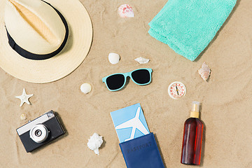 Image showing travel tickets, camera and hat on beach sand