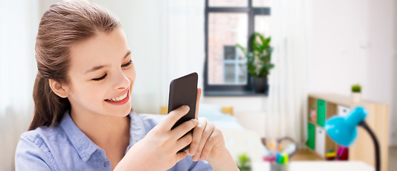 Image showing smiling girl messaging on smartphone at home