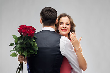 Image showing woman with engagement ring and roses hugging man