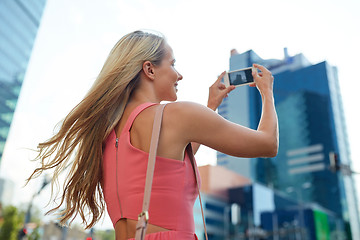 Image showing young woman with smartphone photographing city