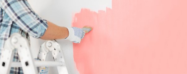 Image showing close up of male in gloves painting a wall