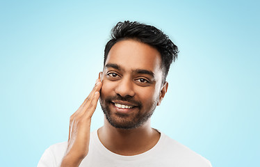 Image showing smiling indian man touching his face