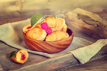 Image showing Croissants with raspberries on a wooden tray. The concept of a wholesome breakfast.