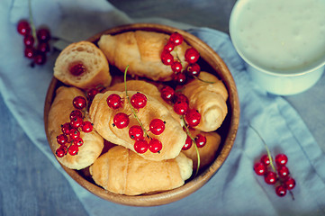 Image showing Croissants with currant berries on a wooden tray.